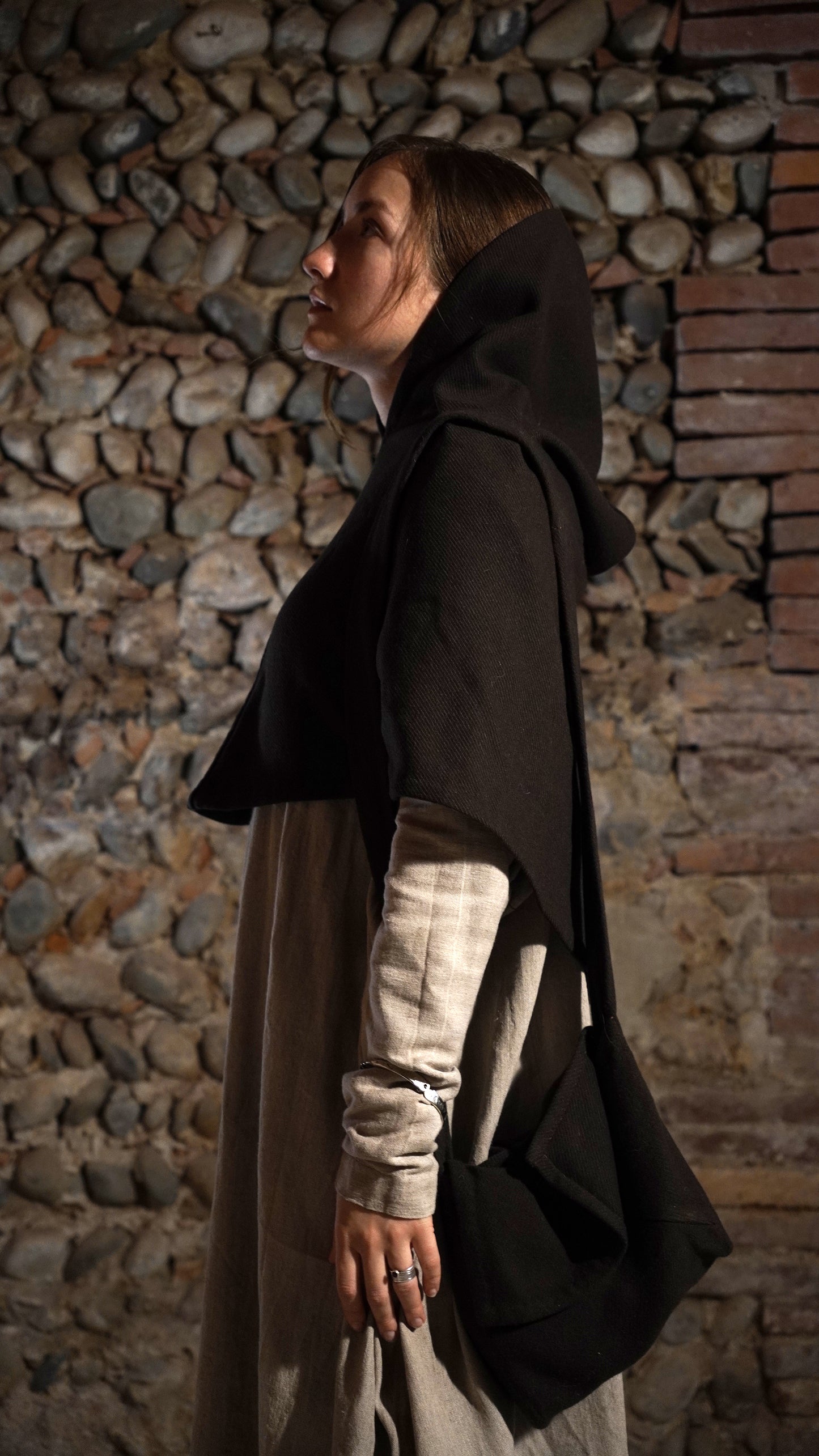 Woman wearing Roman hood and a bag standing side to front