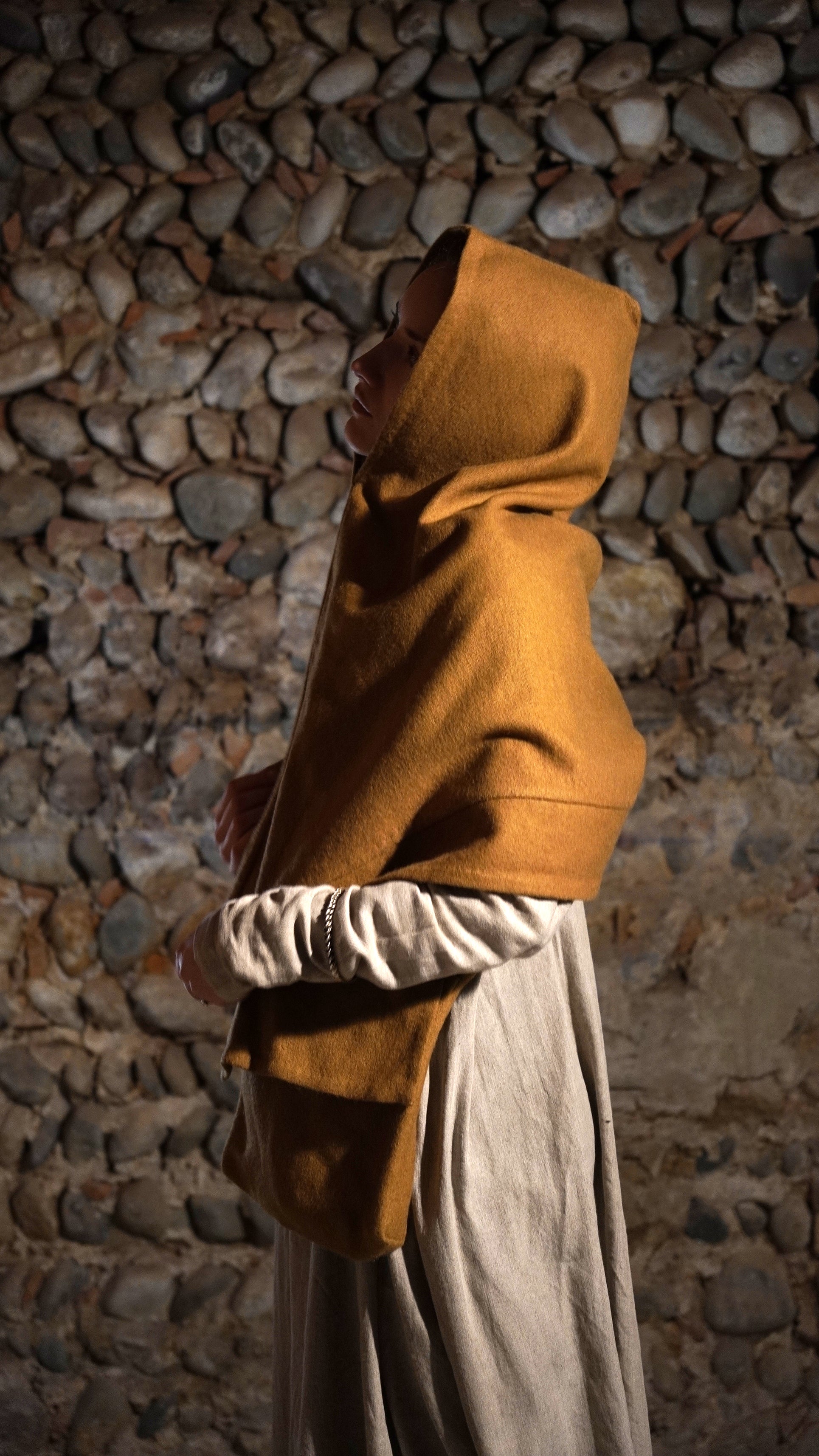 Woman wearing Roman hood and a bag standing side to front