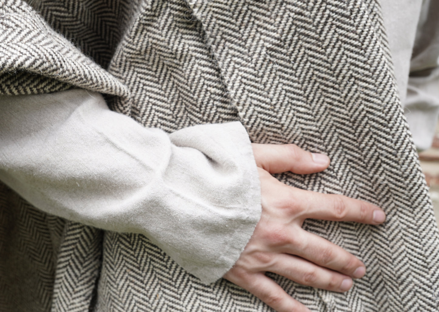 man dressed with Handwoven Herringbone Twill Cloak on tunik held by hand closeup view