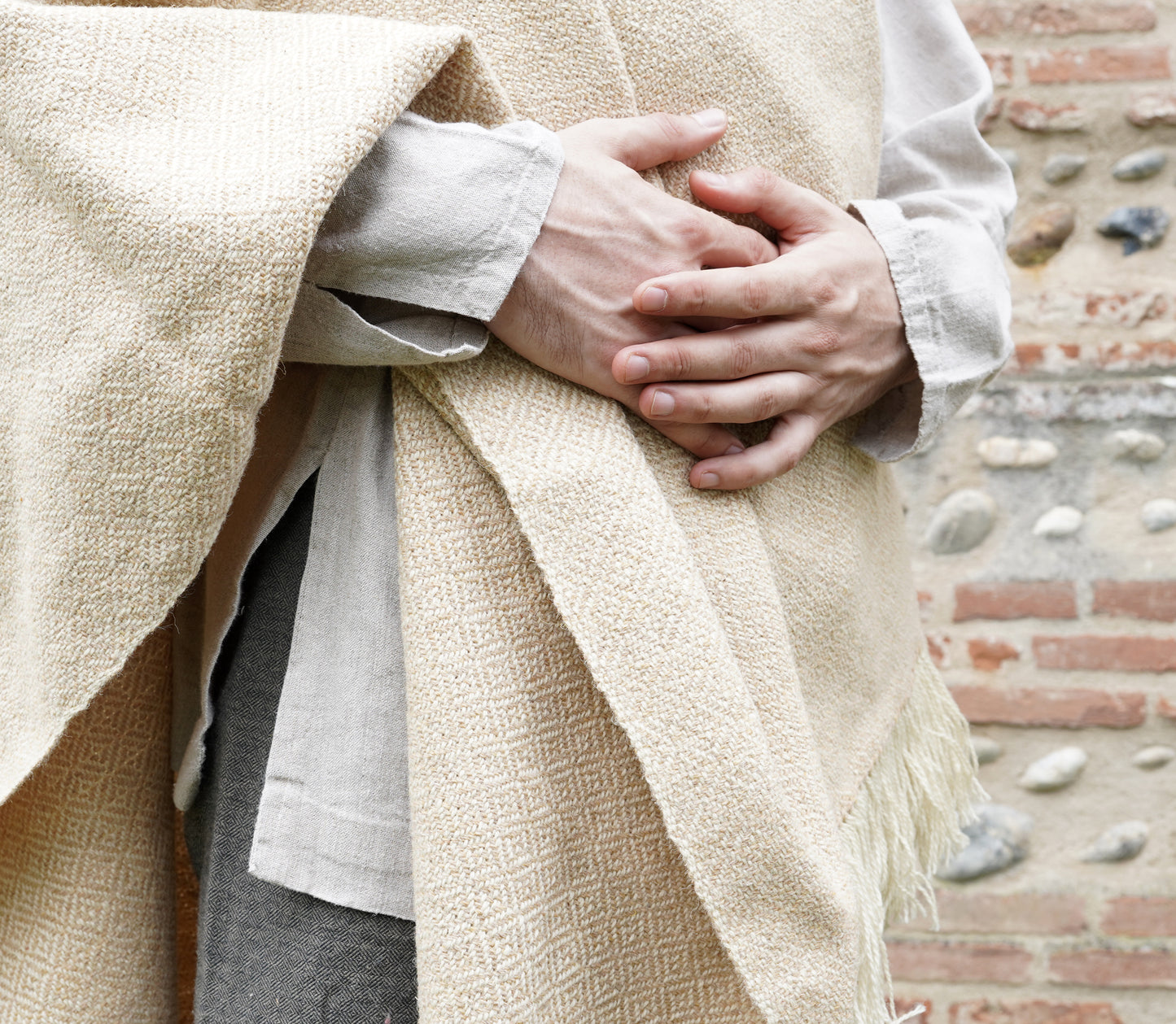 man dressed with Handwoven Diamond Twill Cloak  on tunik held by hands